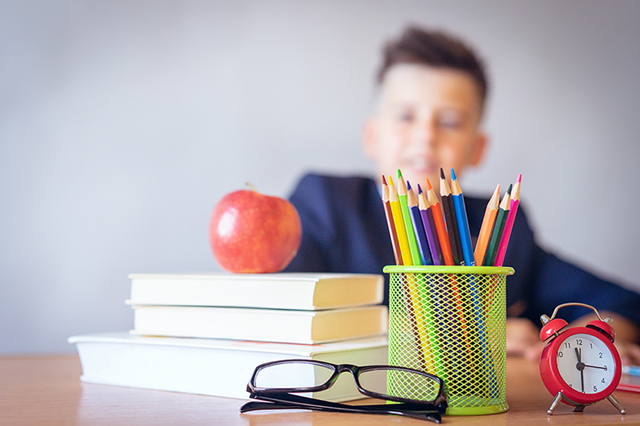 book and pencil holder on a desk with a boy in the background