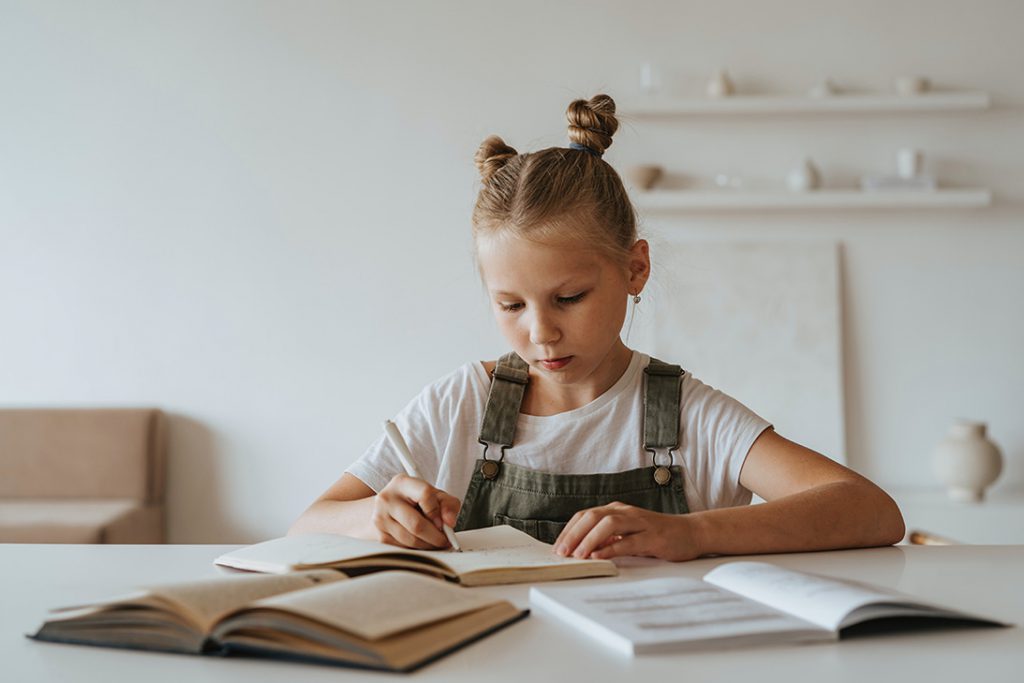 young girl doing homework in a book